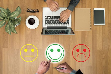 Hand typing in a laptop while the other pointing a smiley face